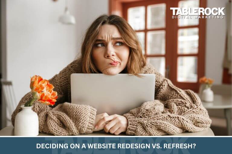 A woman at her laptop deciding on a website redesign vs. a refresh